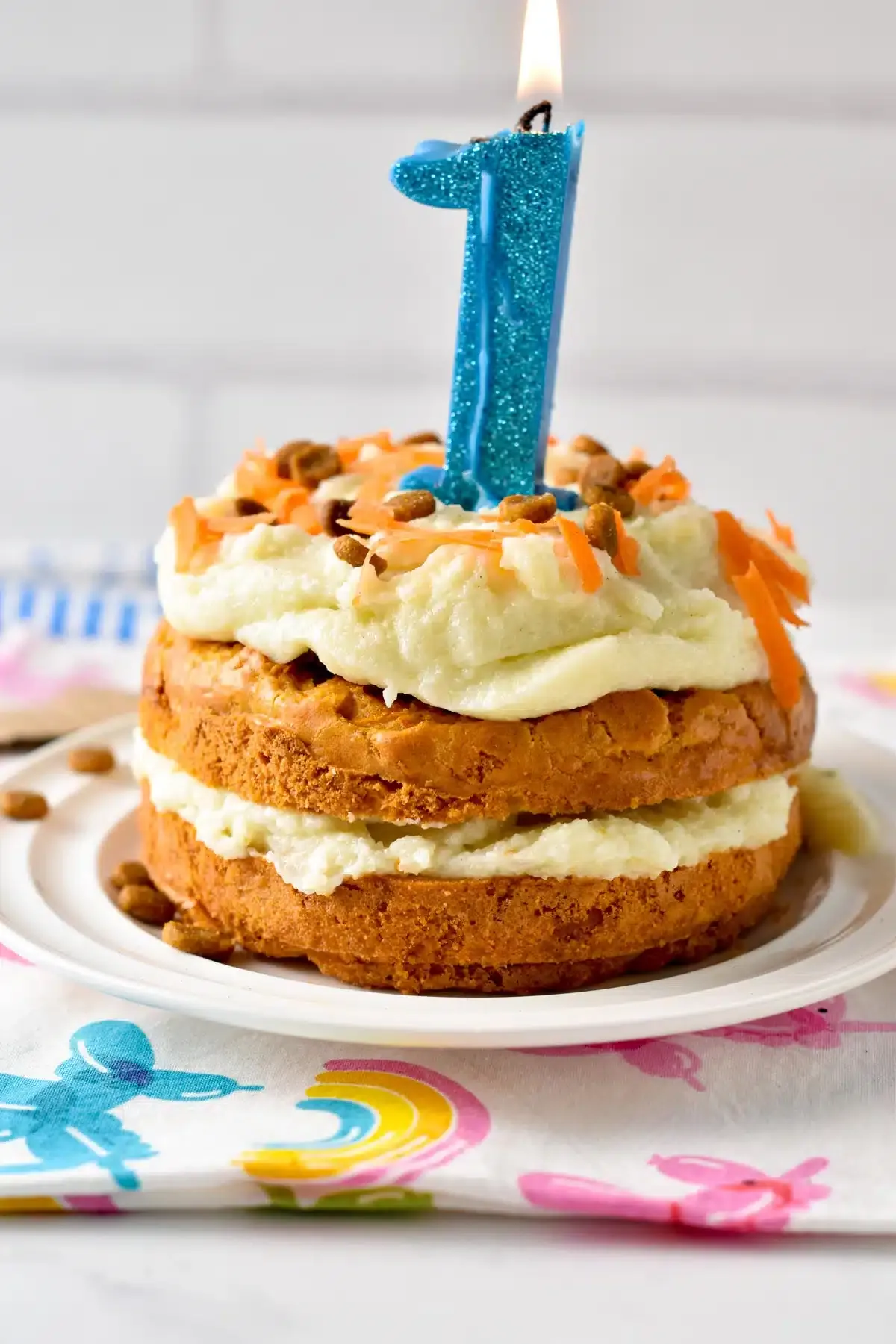 A 3-ingredient Dog Cake Recipe topped with mashed potato frosting and a 1 year old blue candle.