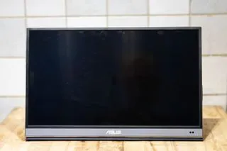 A black and silver ASUS ZenScreen MQ16AH portable OLED monitor set up on a wooden desk