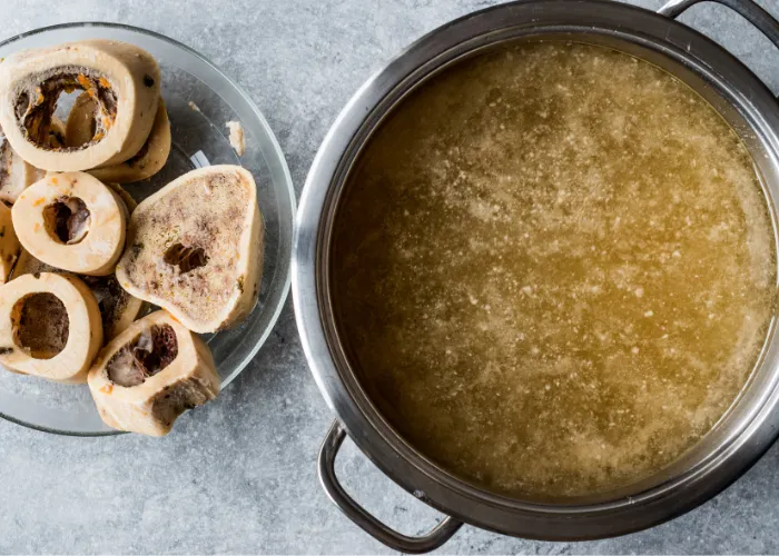A bowl of bone broth made with raw bones, water, carrots, and celery