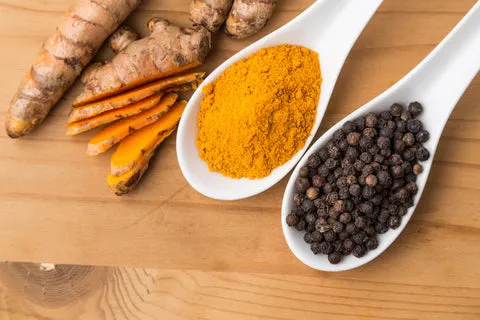A bowl of golden-colored bone broth for dogs with a sprinkle of turmeric on top