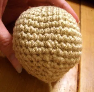 A brown and black crochet dog's finished head, shaped like a teacup terrier