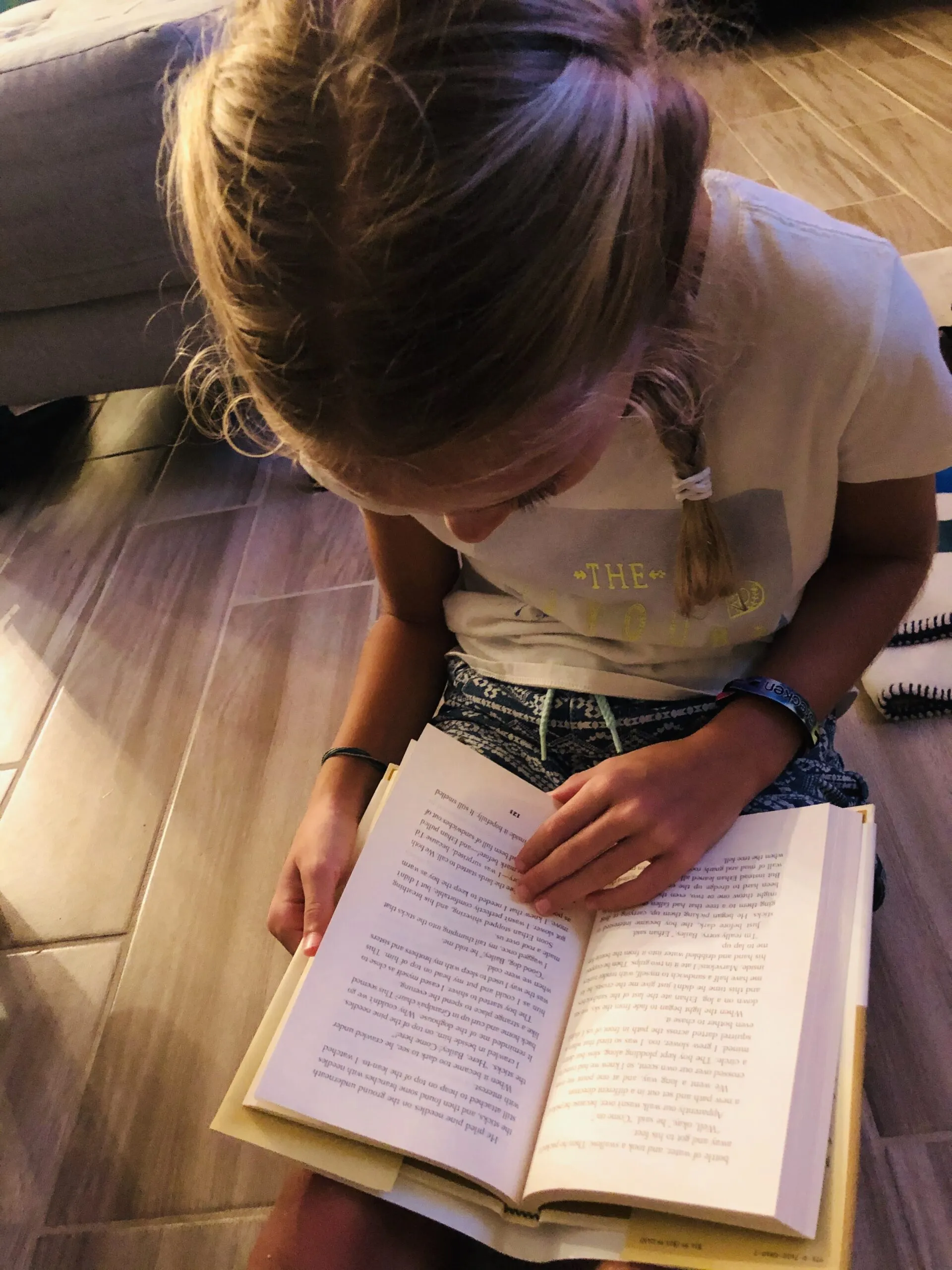 A close-up of a blonde girl with braids passionately reading "Bailey's Story: A Puppy Tale," highlighting the immersive experience for young dog lovers.