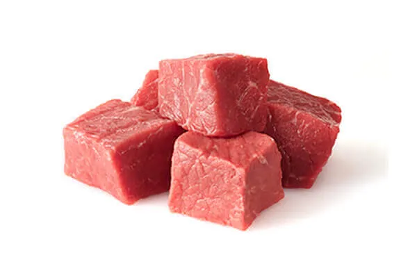 A close-up of ingredients, including beef, brown rice, carrots, and blueberries.