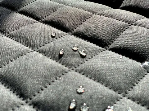 A demonstration of a single dog car seat cover with a waterproof backing, highlighting its protective qualities against spills and moisture.