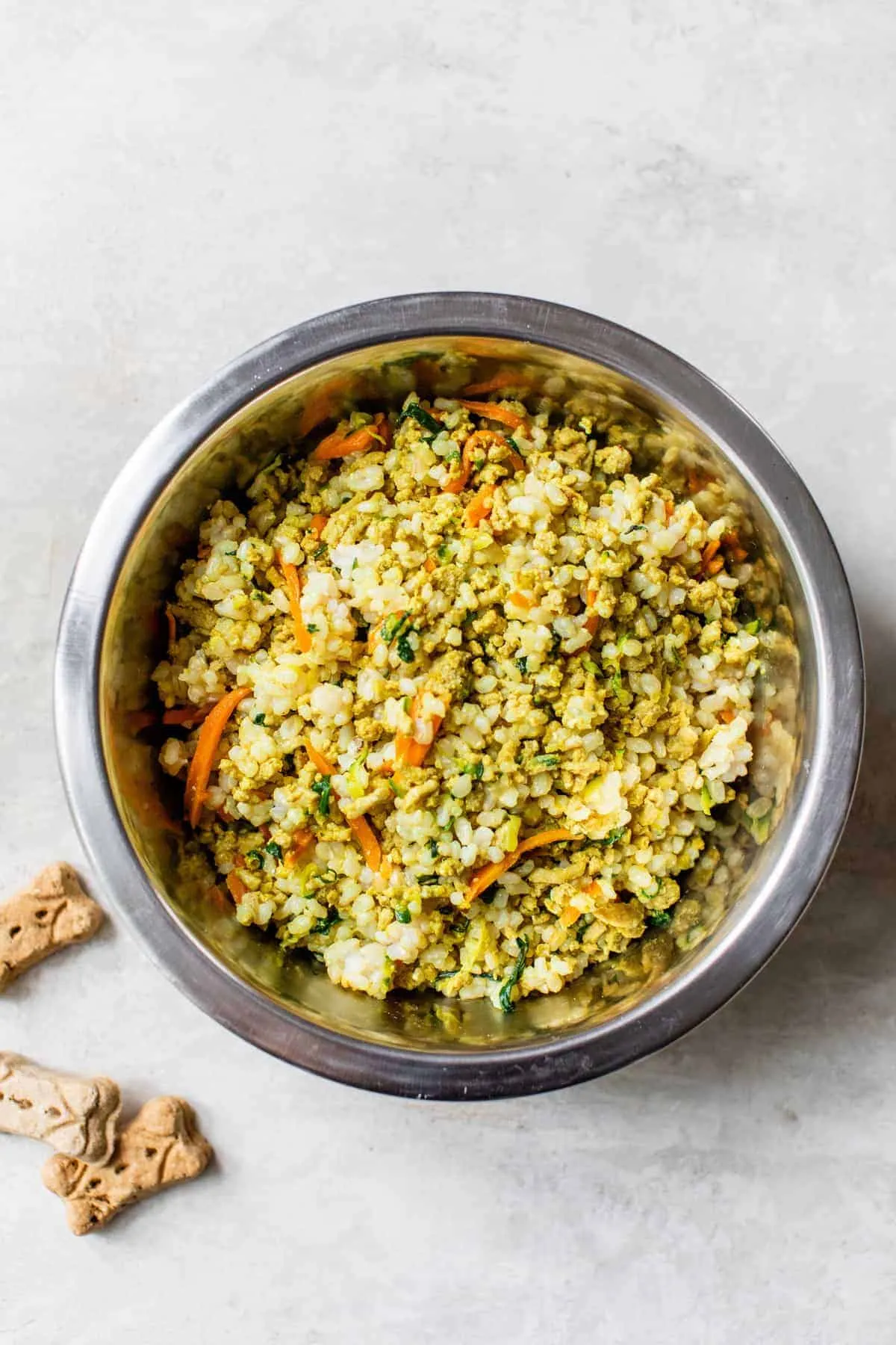 A dog dish filled with homemade dog food, surrounded by dog treats.