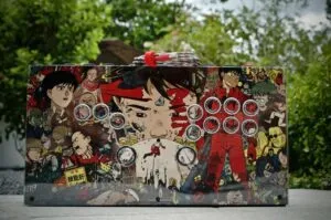 A flat arcade-style control board with several buttons, featuring anime-style art with trees in the background.