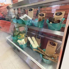 A selection of dog treats, including bully sticks and pig ears, displayed in bulk packaging
