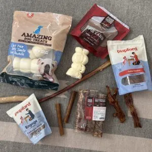 A variety of dog chews, showcasing different textures and shapes, are displayed on a white surface.