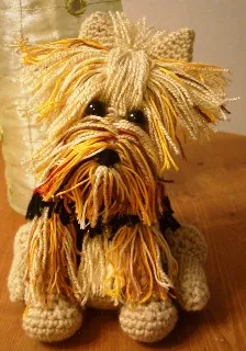 A very small Yorkshire Terrier puppy, often referred to as a teacup Yorkie, standing on a human hand.