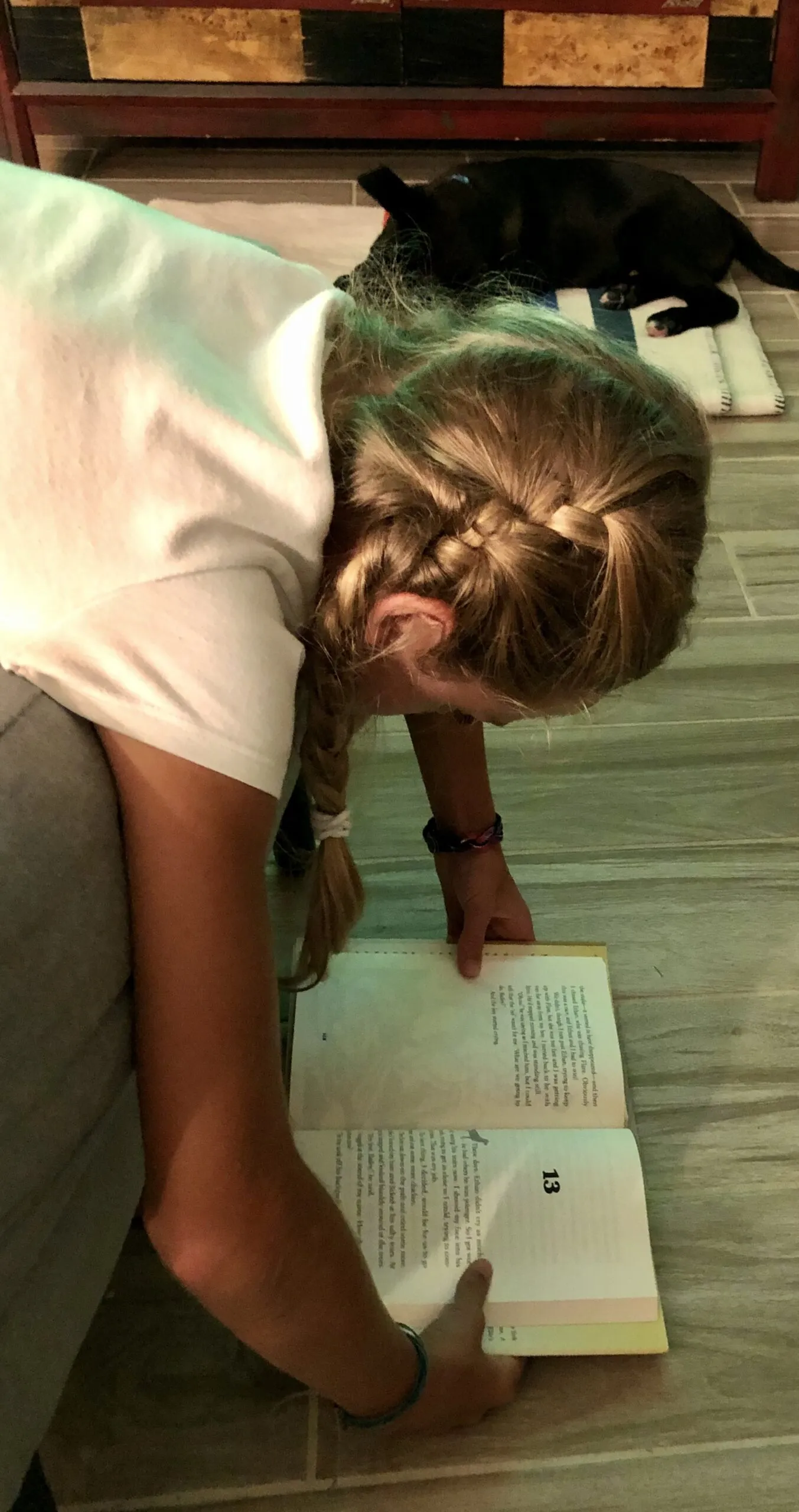 A young girl engrossed in reading "Bailey's Story: A Puppy Tale," holding the book upside down, illustrating a child's deep connection to the golden retriever's adventures.