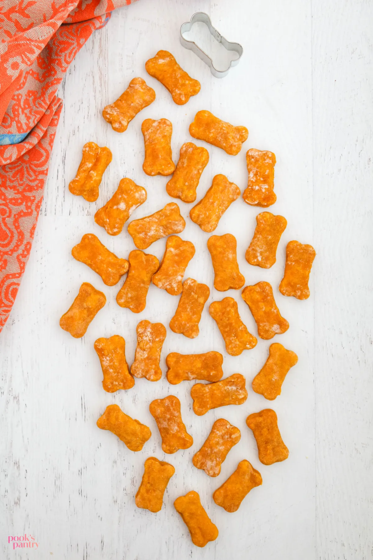 An appealing presentation of treats for senior dogs set against a clean white background, with a vibrant orange towel adding a splash of color to the side.