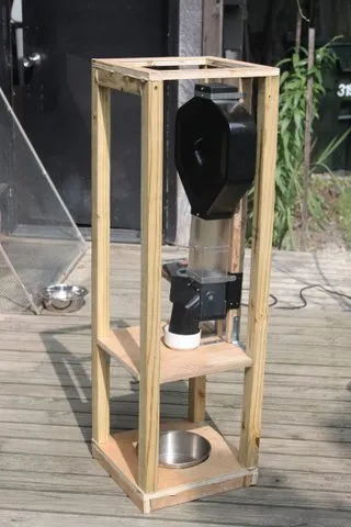 An extra large automatic dog feeder set up outdoors with a large dog enjoying its meal.