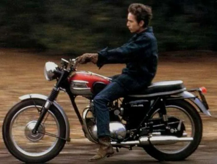 Bob Dylan on his 1964 Triumph Tiger motorcycle, a symbol of his rebellious spirit and pursuit of freedom in the mid-1960s