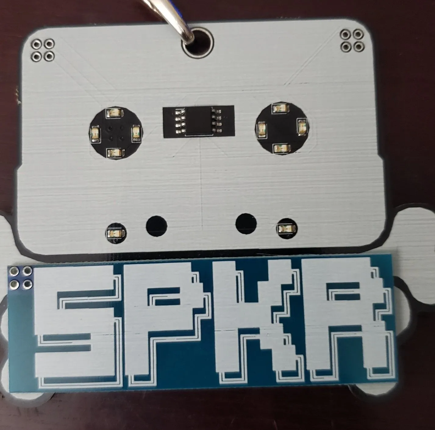 BSides Conference Badge front view, a small circuit board with various components and LEDs, demonstrating a target for hardware hacking