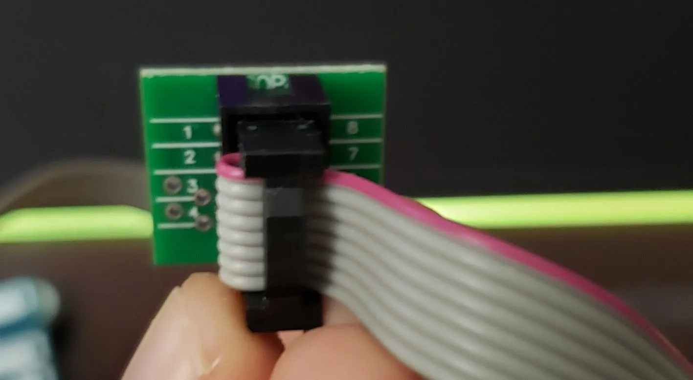 Close-up of a SOIC clip, highlighting its eight metallic contacts and the internal structure designed for chip attachment