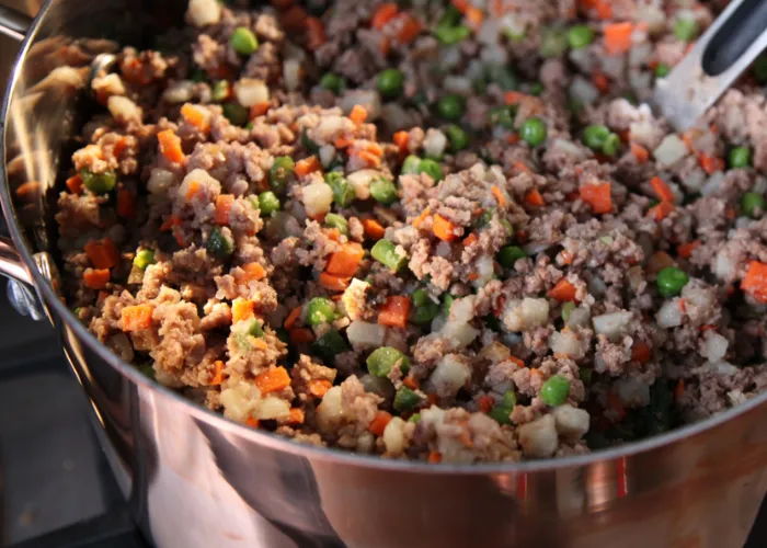 Cooked venison, sweet peas, and quinoa mixed with coconut oil in a serving dish.