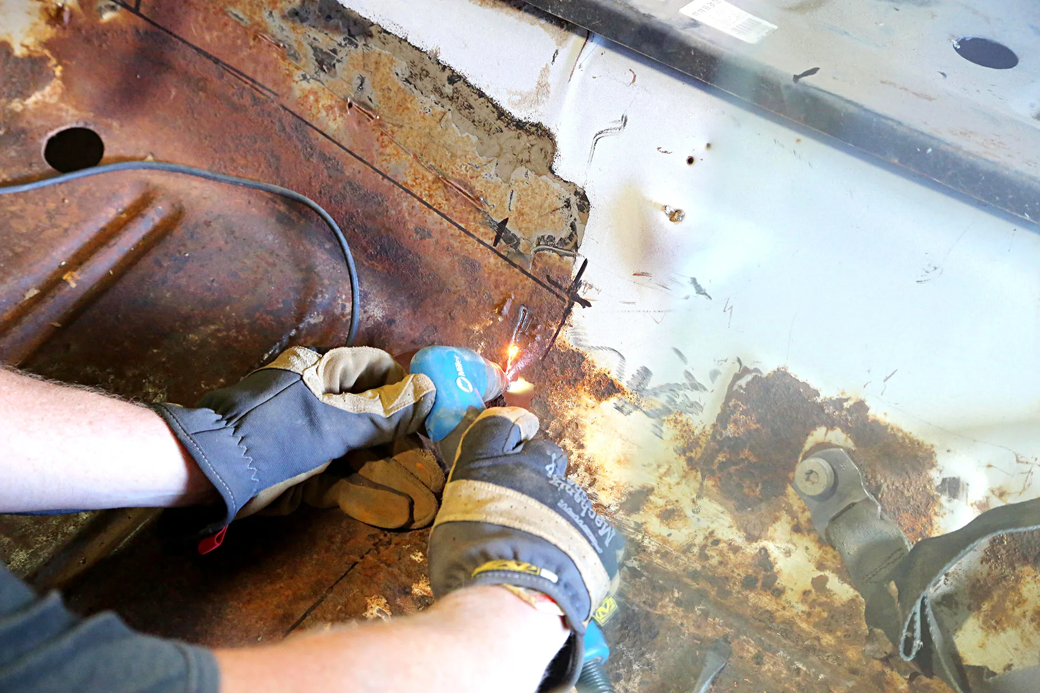 Cutting out the old rusted floor pan near the transmission tunnel using a plasma torch on a 1969 Mustang