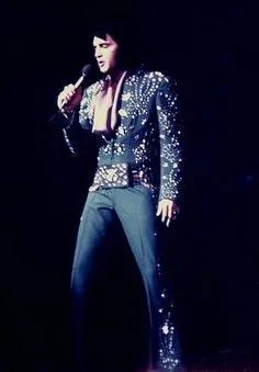 Elvis in concert in Las Vegas, performing his signature moves in a sparkly white jumpsuit.
