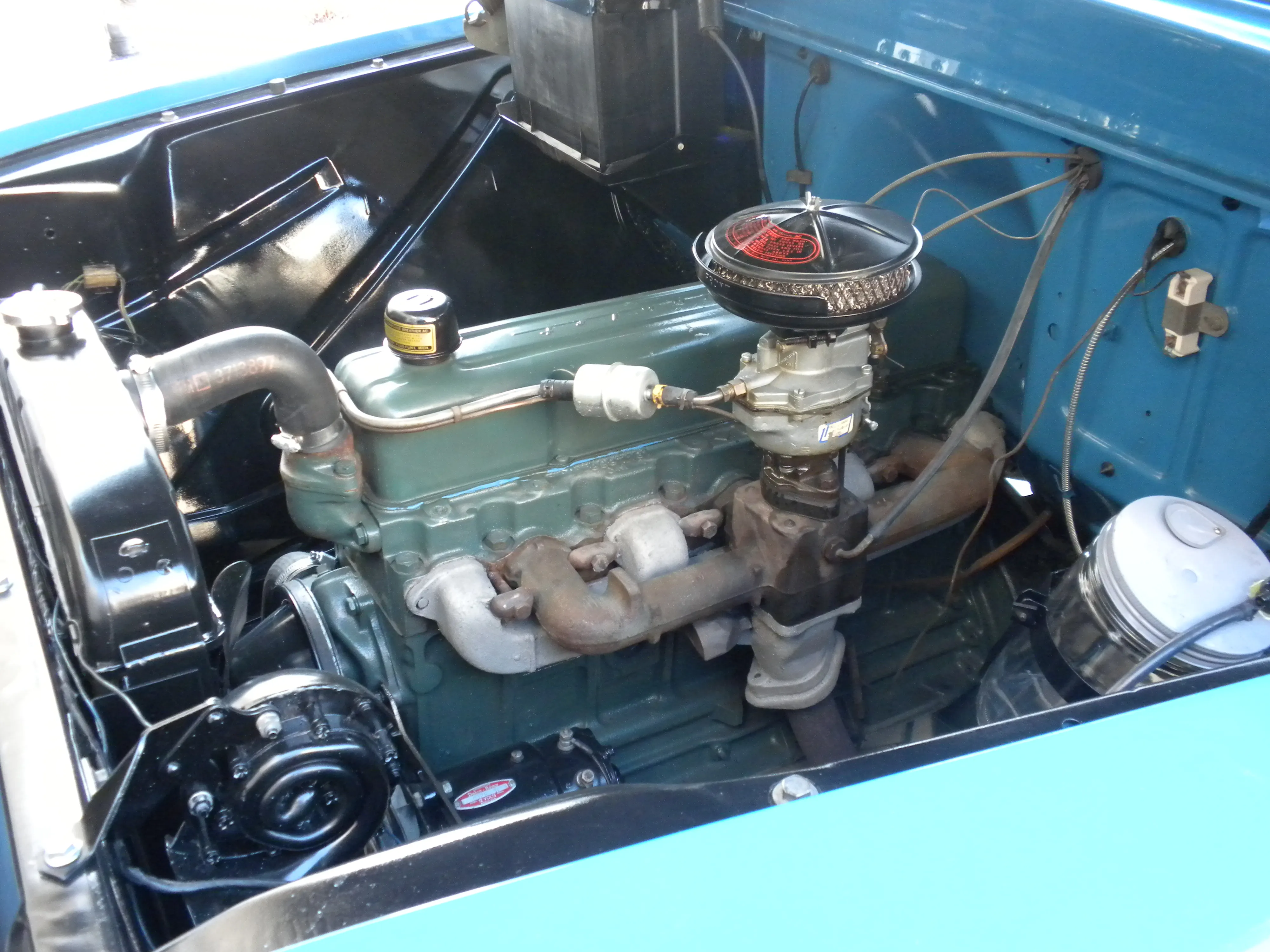 Engine compartment of the 55 Chevy truck, showing the reinstalled original windshield washer system components.