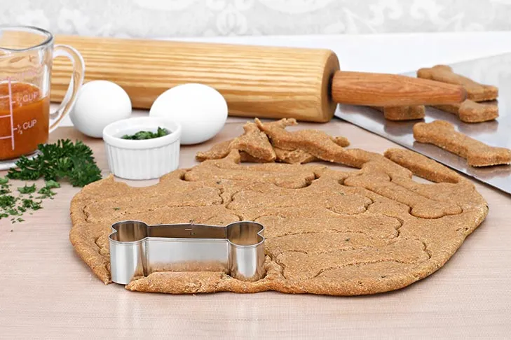 Essential baking supplies and ingredients laid out for making healthy homemade dog biscuit treats.