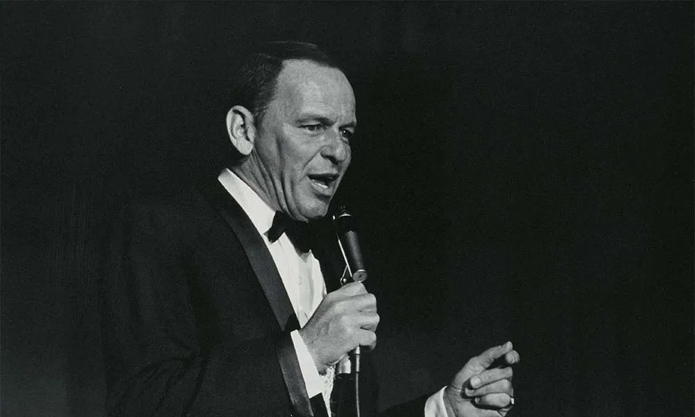Frank Sinatra performing live at Royal Festival Hall in London, 1962, his iconic silhouette against the stage lights.