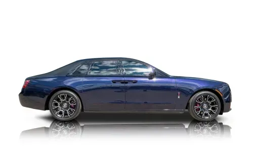 Front side view of a dark blue 2024 Rolls-Royce Ghost Black Badge parked in a modern setting