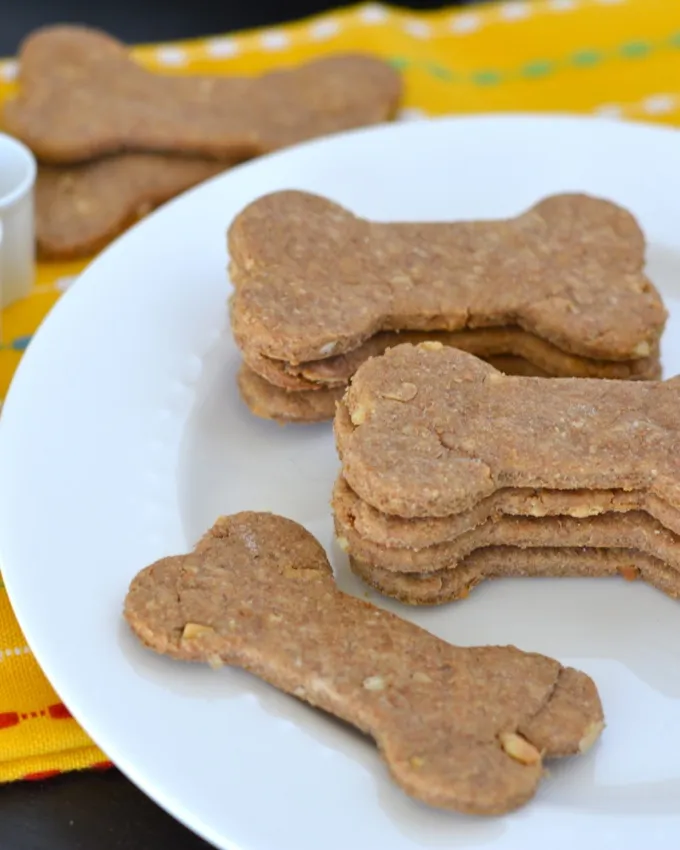 Golden-brown bone and paw shaped homemade peanut butter dog treats on a cooling rack