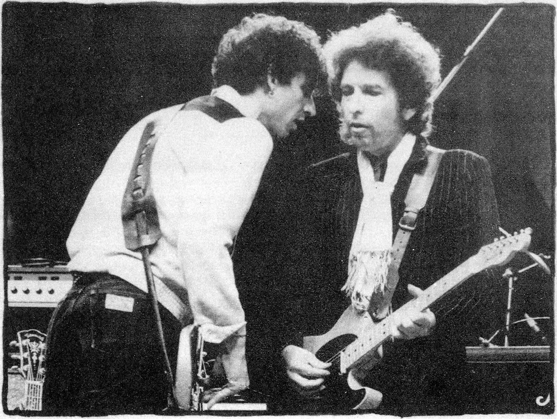 Gregg Sutton on stage, playing his bass guitar with intense focus during Bob Dylan's 1984 tour.