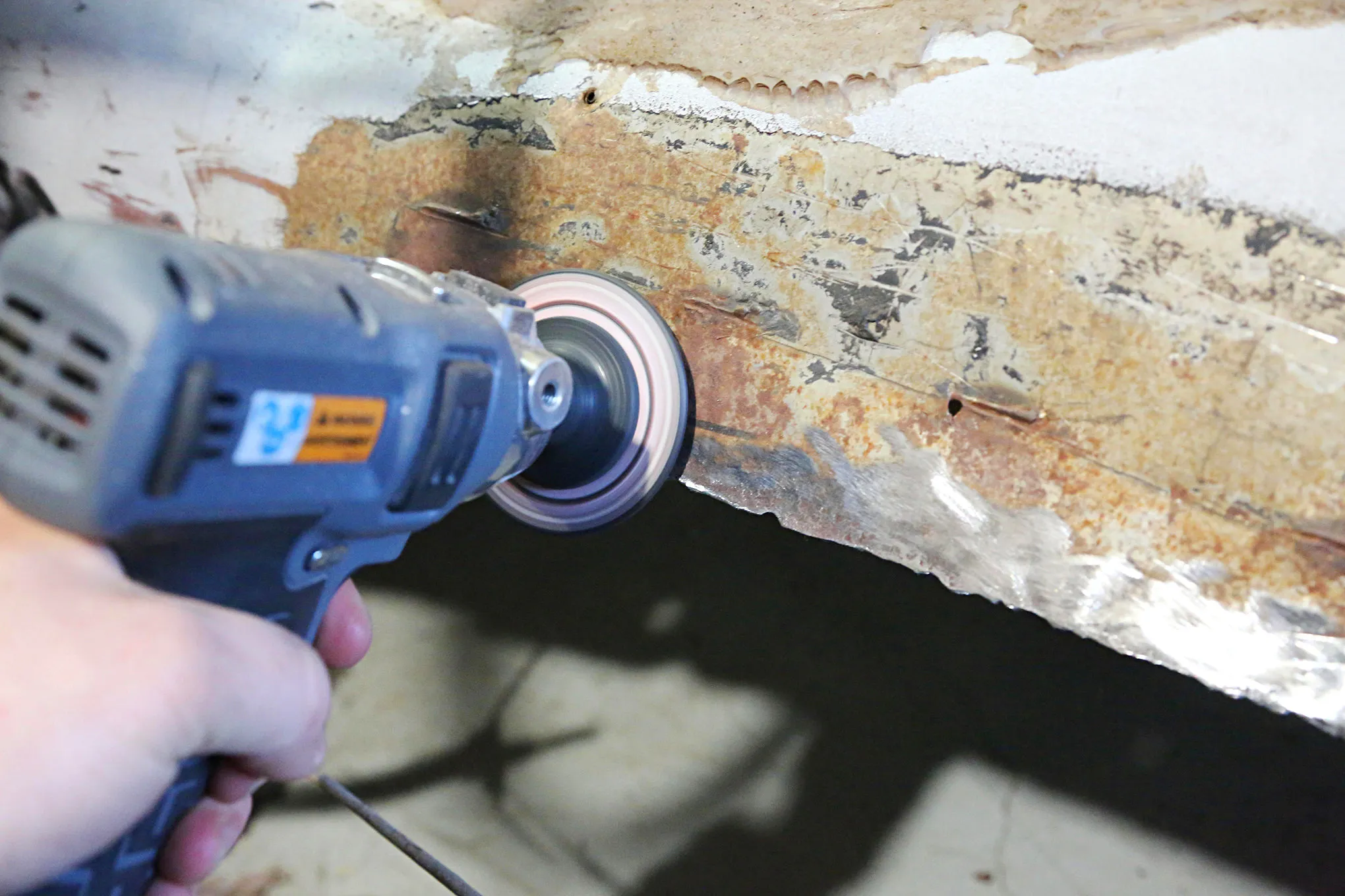 Grinding rust and preparing metal edges for welding a new floor pan into a 1969 Mustang Coupe