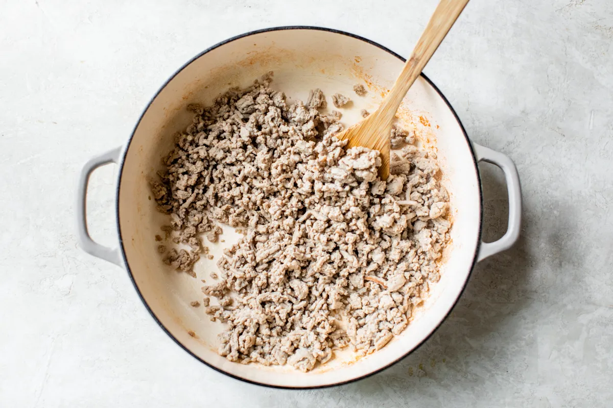 Ground turkey browning in a large stainless steel pot, preparing for homemade dog food recipe