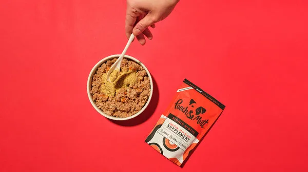 Our Bionic Biotic powder supplement, sprinkled over a bowl of dog food, on a red background
