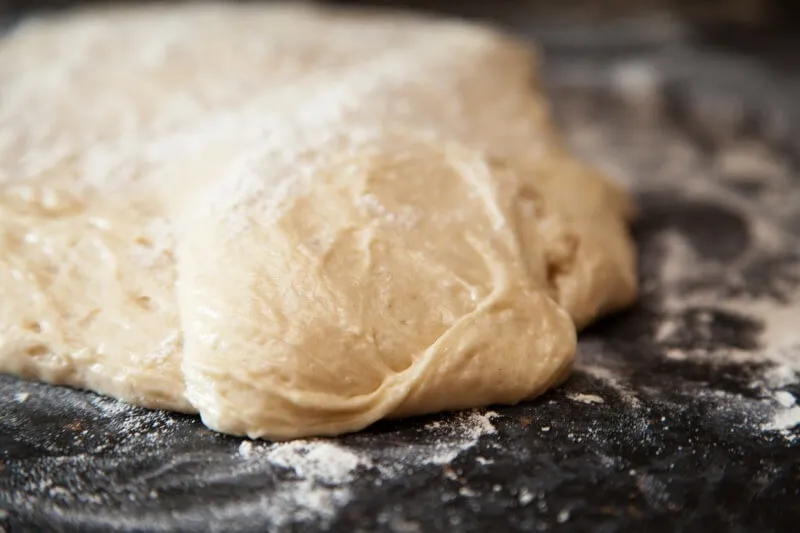 Raw yeast dough in a bowl, representing the dual danger of expansion and alcohol for dogs.