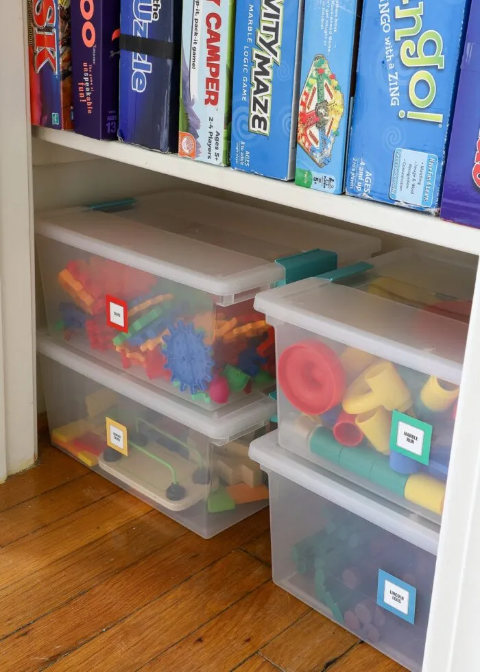 STEM games loaded into Sterilite plastic tubs in the bottom of an organized game closet