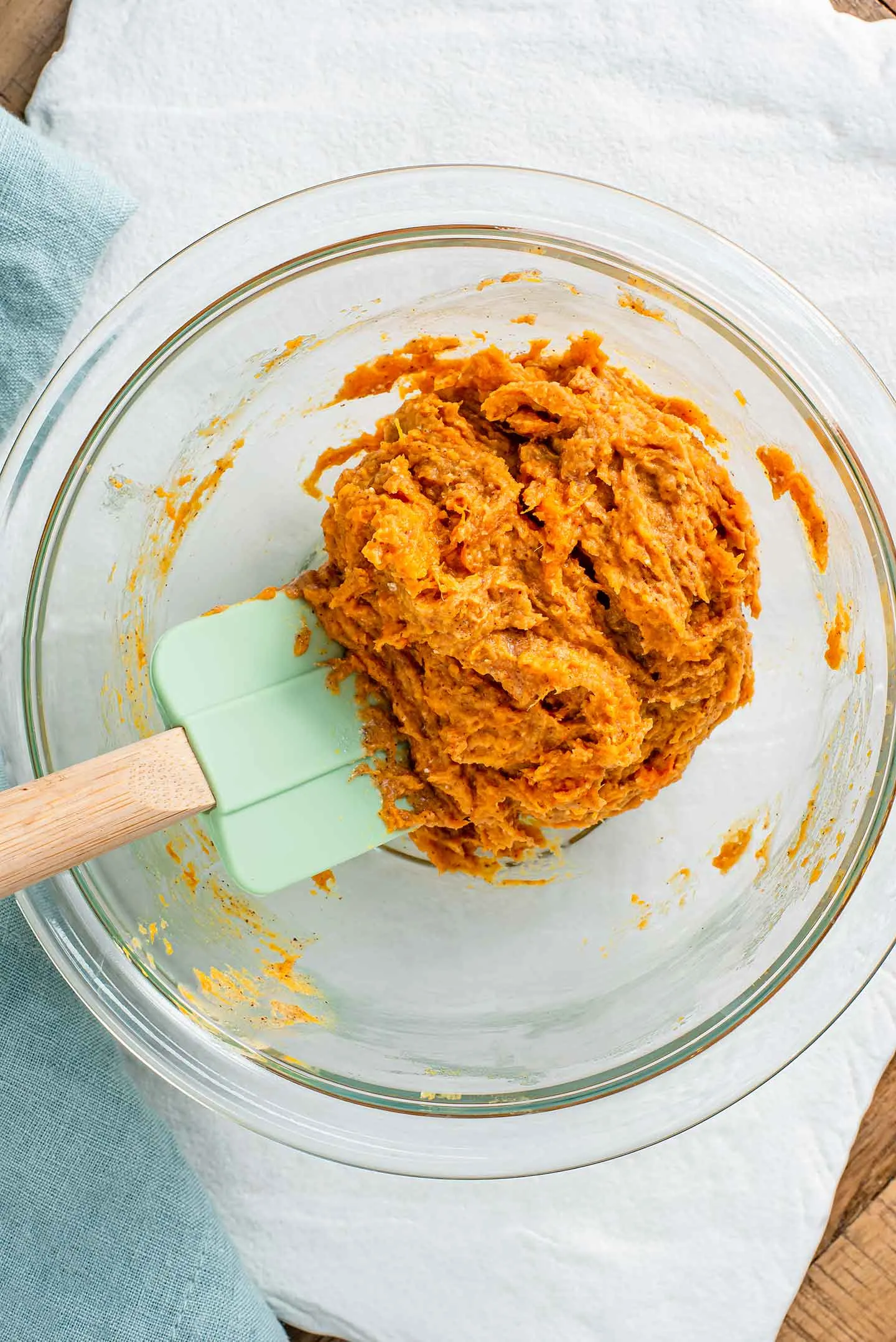 Top down view of a rubber spatula combining mashed sweet potato and peanut butter for home-made dog treats.