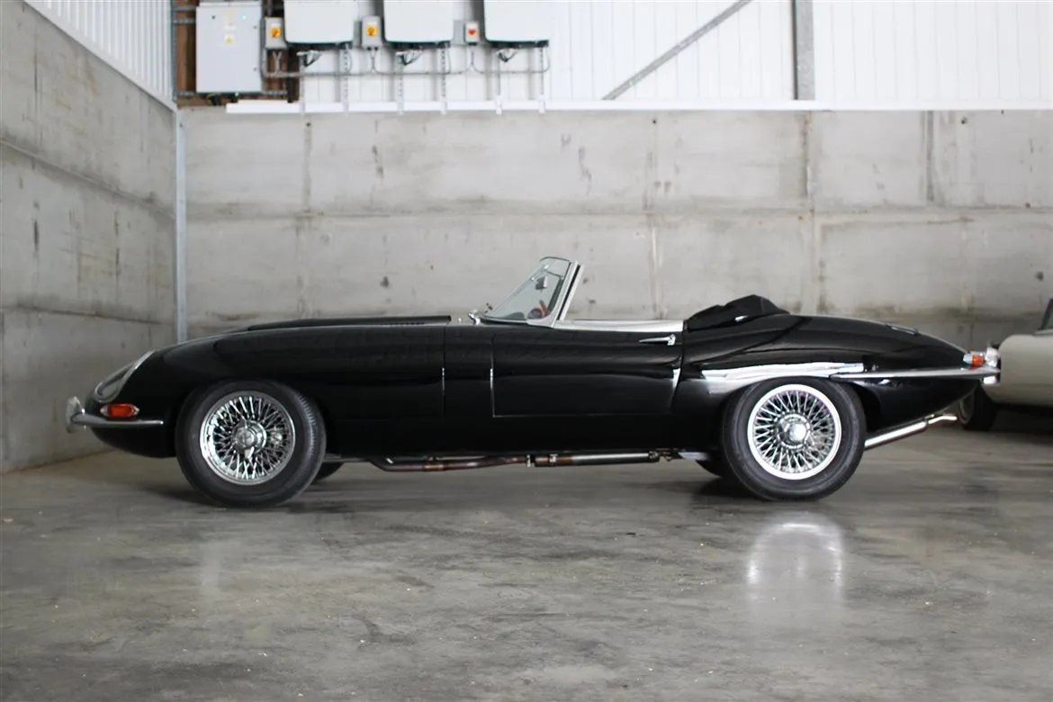 A beautifully restored Jaguar E-Type Series 1 Fixed Head Coupé, showcasing its classic lines and original engine bay design.