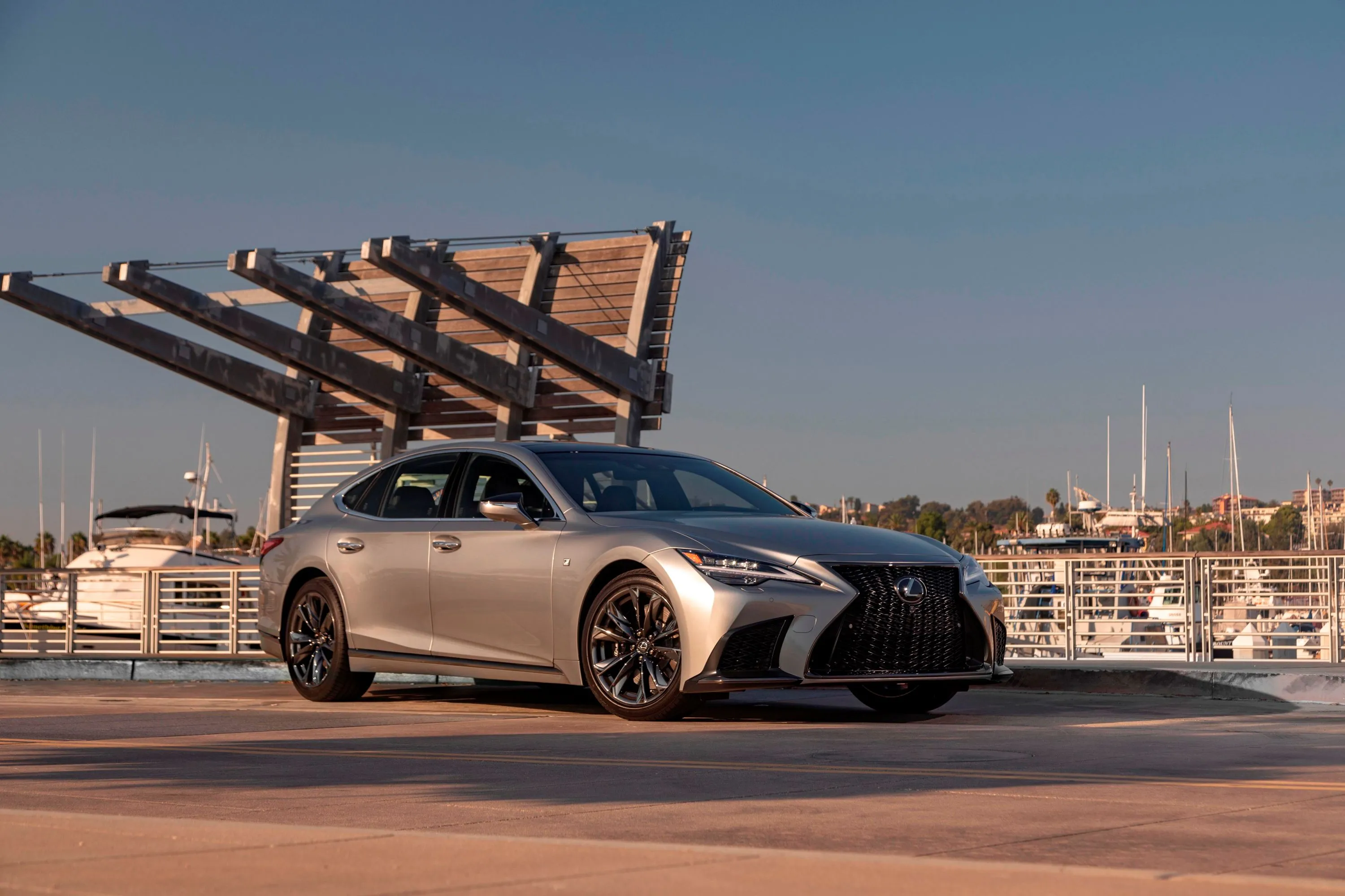 A black Lexus LS luxury sedan parked in a futuristic, illuminated garage