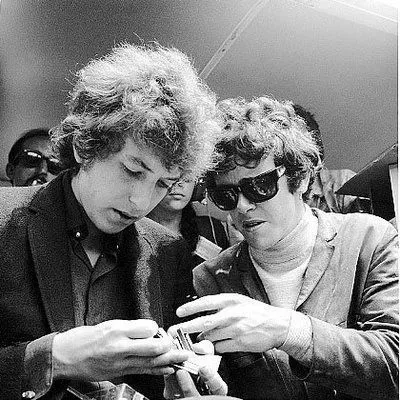 A candid black and white shot of Bob Dylan and Donovan sharing a moment.