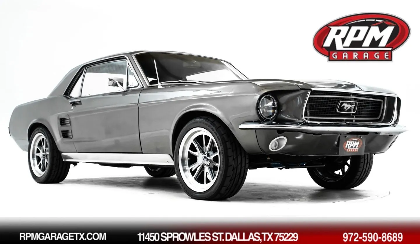 A classic gray 1967 Ford Mustang coupe with black interior, seen from the front three-quarter angle