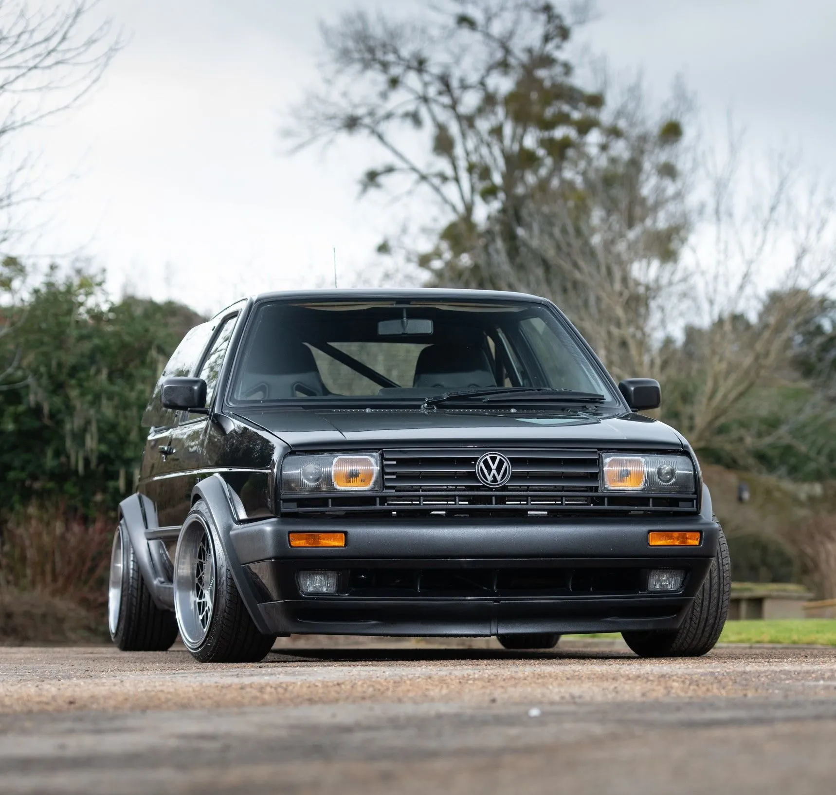 A classic white Volkswagen MK2 Golf hatchback, meticulously maintained, shown indoors