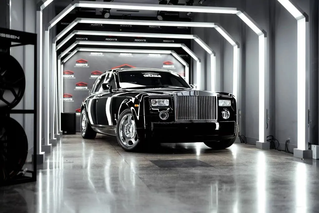 A close-up of the dashboard and steering wheel of a 2008 Rolls-Royce Phantom, highlighting the premium leather, wood veneers, and polished metal accents.
