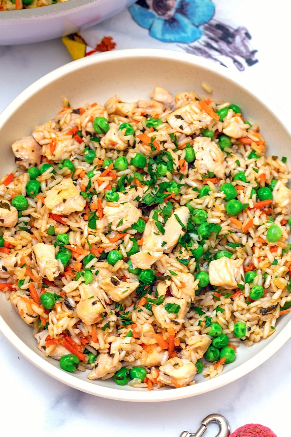 A close-up view of a bowl filled with homemade chicken and rice dog food, garnished with fresh green peas and shredded orange carrots.
