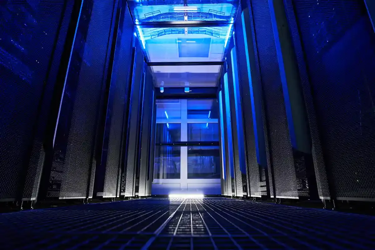 A long row of server racks bathed in blue light within a modern data center at night