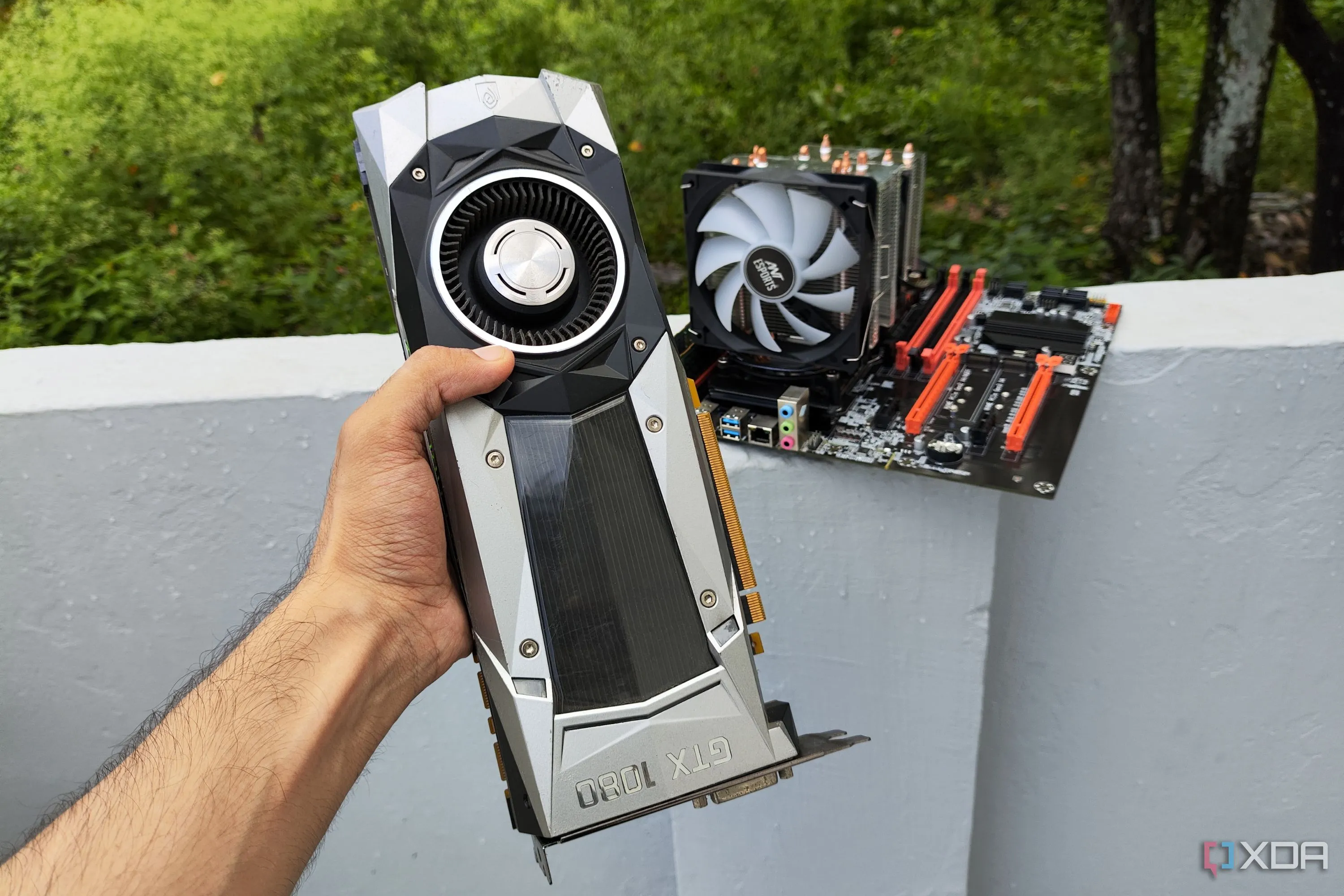 A person holding a GTX 1080 Founders Edition GPU in front of a server PC, emphasizing its use in specialized projects.