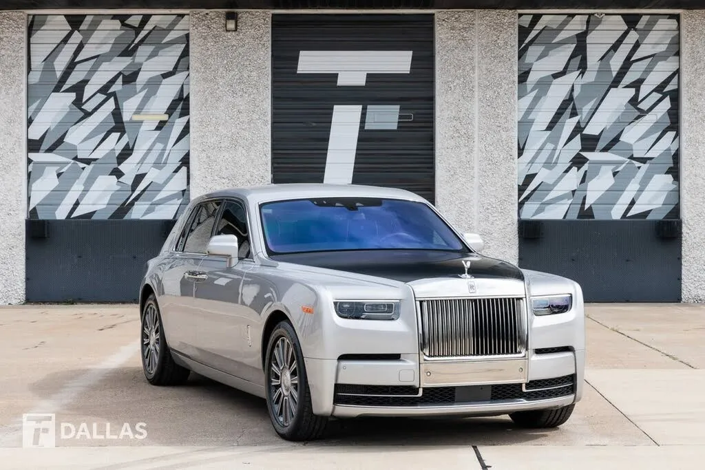 A pristine white Rolls-Royce Phantom parked gracefully at a dealership