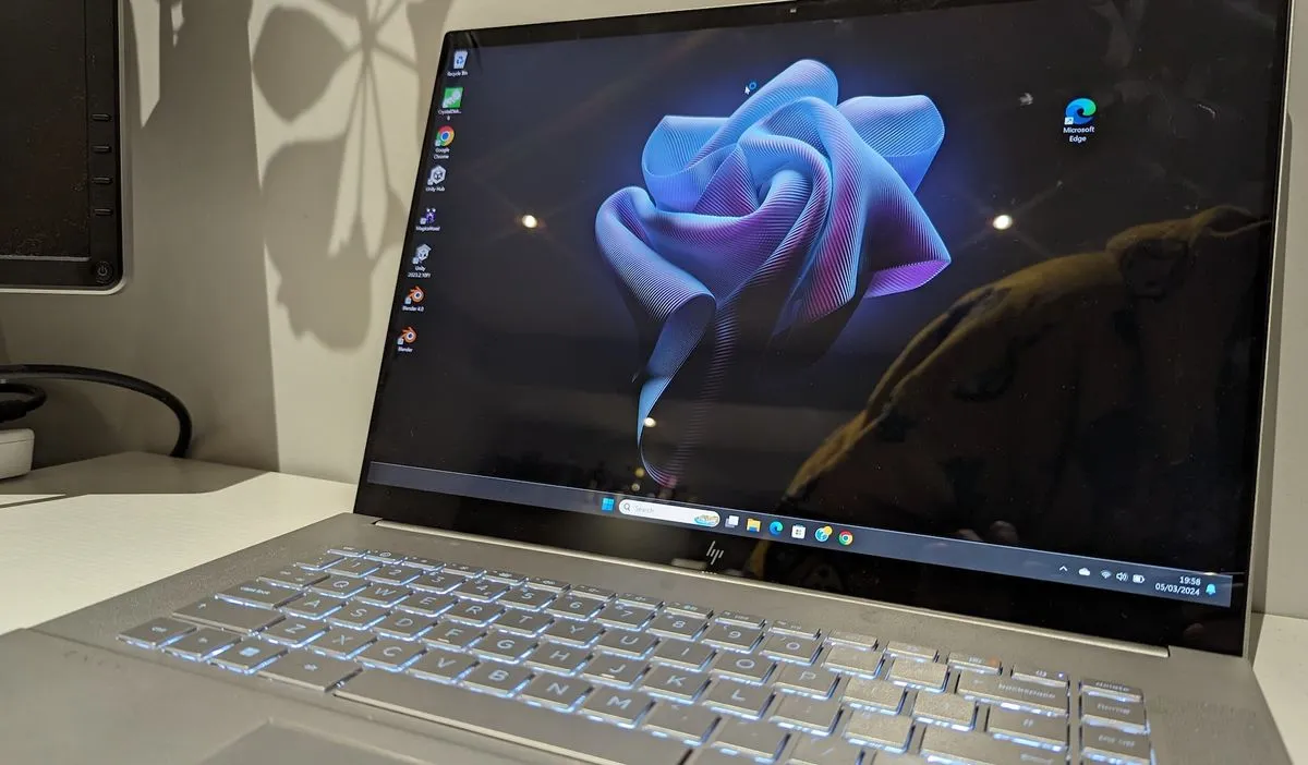 A silver HP Envy 16 laptop sitting on a table with its lid slightly ajar, showcasing the screen.