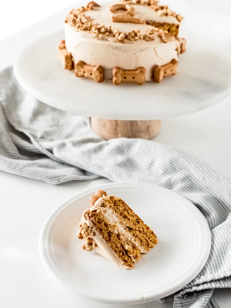 A slice of pumpkin dog cake with creamy peanut butter yogurt frosting on a white plate.