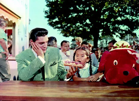 A vibrant color still from "It Happened At The World's Fair" showing Elvis Presley performing on screen