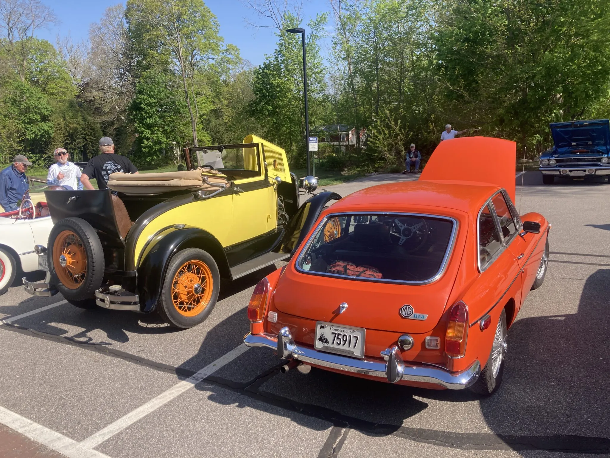 A vintage Model A Ford and an MGB GT parked side-by-side at an outdoor car show, capturing the essence of classic British and American automotive design.