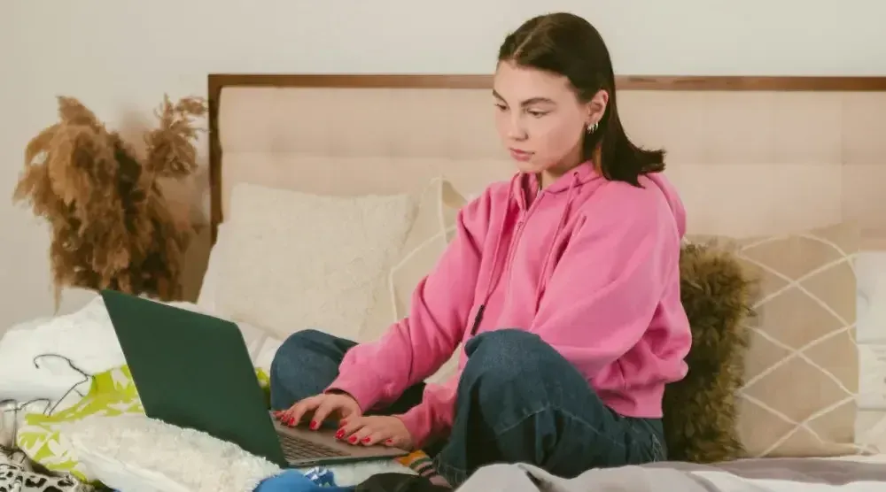 A young woman works diligently on her pet walking business finances at a desk, reflecting the dedication required to manage a successful venture.