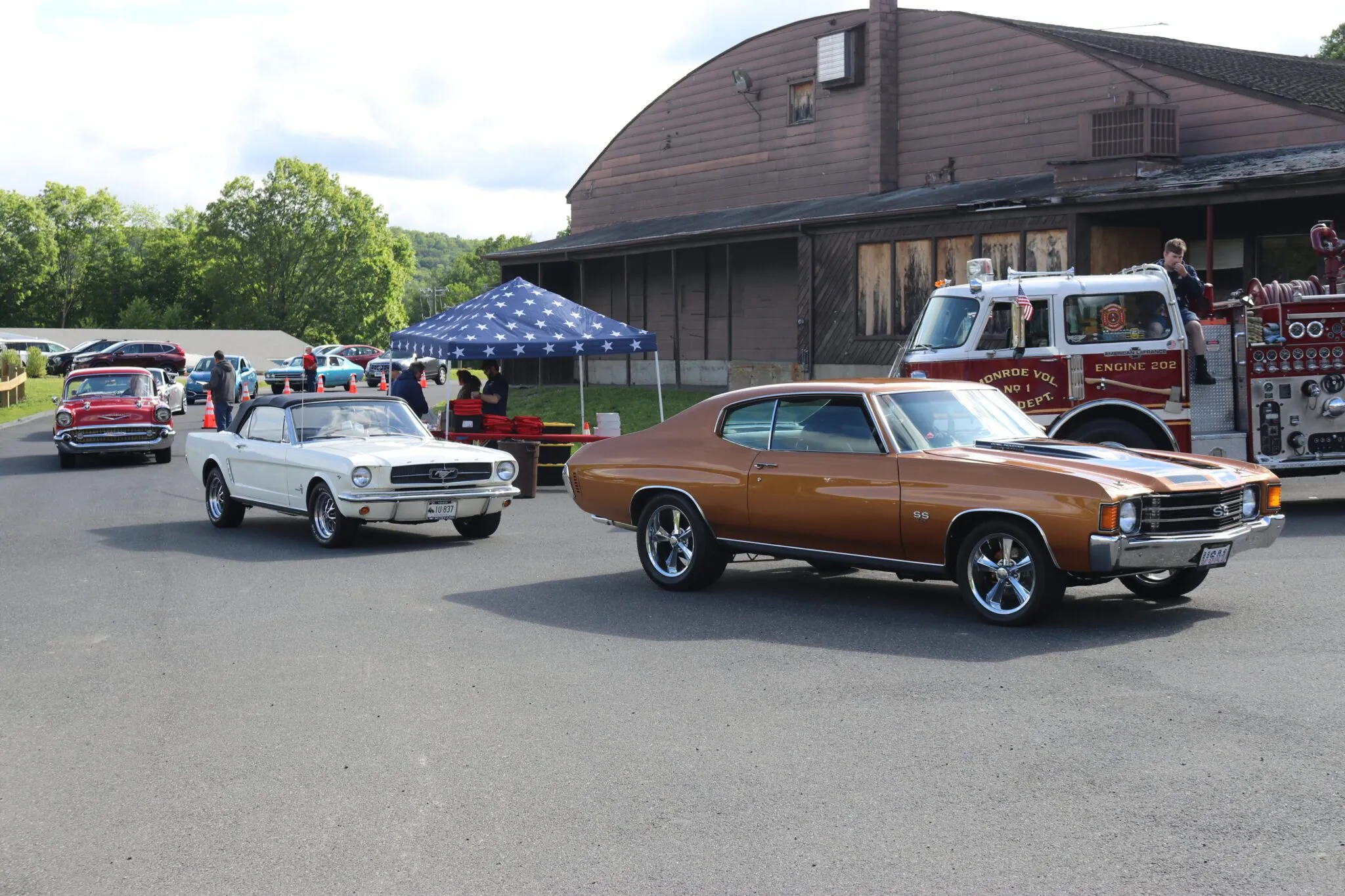 Attendees gather around an antique car at the Barnum Festival Car Show, with a vibrant atmosphere.